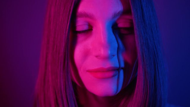 Mysterious tricky stunning young woman looking around. Close-up footage of face. Bob hairstyle. Neon lighting. Beautiful hair. Purple. Colorful. Lit. Amazing, modeling