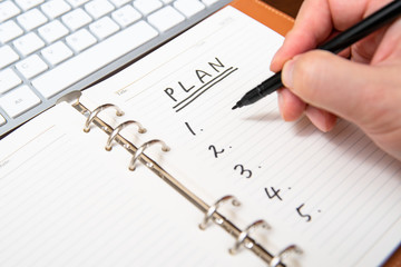 Close-up of a businessman's hand writing plan and list in the diary.
