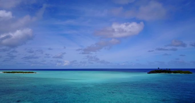 Aerial slow panning footage of a small tropical island with a larger one on the distance in South Pacific, Cook Islands