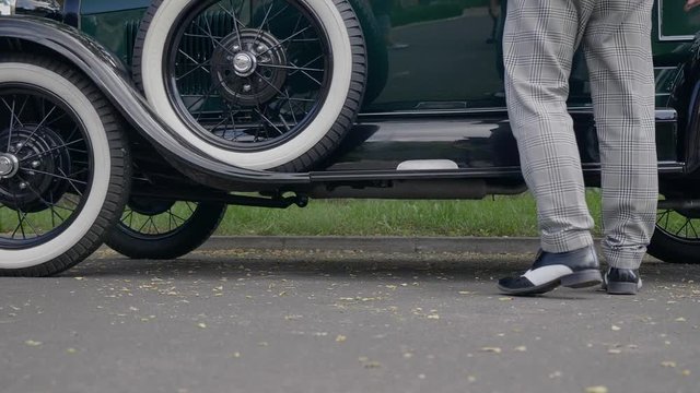 Dressed up man enters vintage car. Slow motion clip. 