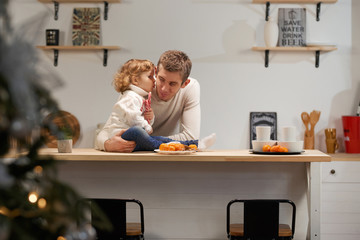 Dad and daughter in the kitchen celebrate Christmas with tangerines or New Year. Care and love, warmth. Horizontal frame.