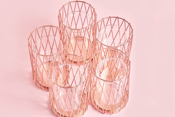 Fototapeta na wymiar metal geometric shape candlesticks in rose gold on a pink background