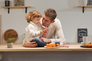 Naklejka premium Dad and daughter in the kitchen celebrate Christmas with tangerines or New Year. Care and love, warmth. Horizontal frame.