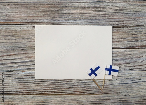 December 6 . Finnish independence day. mini flags on wooden background with white paper sheet