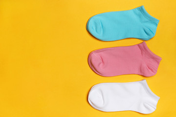 Closeup set of short socks in white, pink, blue on a yellow background with copy space