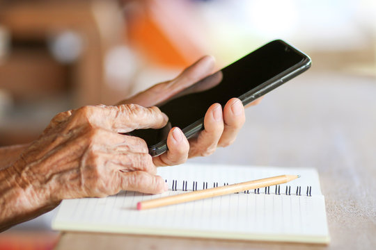 Old woman holding smart phone for shpping online