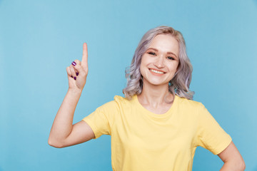 Fototapeta premium Portrait of happy girl pointing something by finger isolated