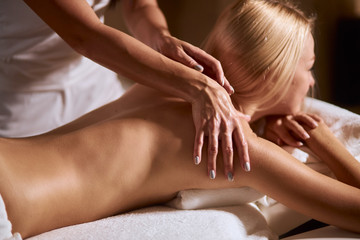 Obraz na płótnie Canvas Blonde young caucasian woman having aroma therapy massage with essential oil, gentle female hands massaging shoulders of carming lady, body care, skin care, wellness , well being concept