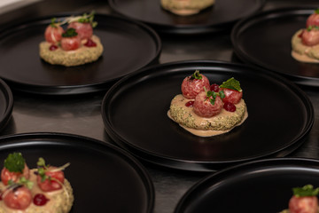 Eggplant phali with tomatoes and pomegranate gel on a black plate.