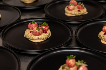 Eggplant phali with tomatoes and pomegranate gel on a black plate.