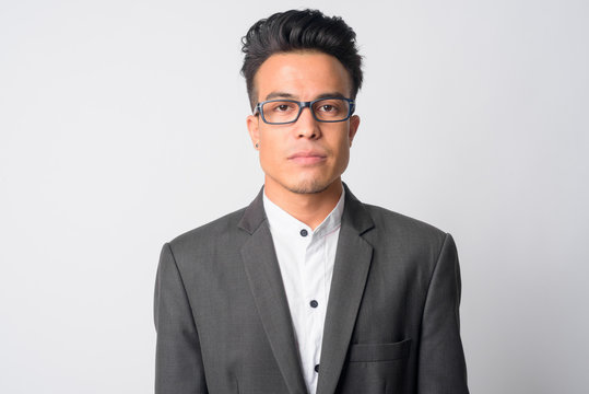 Face of young Asian businessman in suit wearing eyeglasses