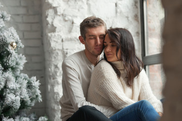 Loving couple on a light background celebrates Christmas. Love, cares, warmth.