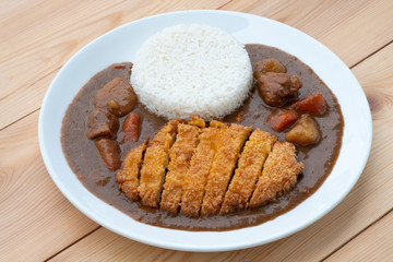 Tonkatsu, Japanese deep-fried pork cutlet on top with curry in white dish on wooden table. Japanese food.