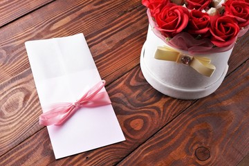 Gift box with flowers on wooden background, preparation for the holiday concept. Top view and copy area for text.