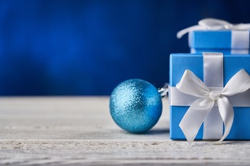 Gift box with Christmas ball on white table. Copyspace for text.