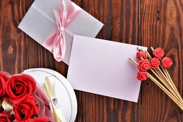 Gift box with flowers on wooden background, preparation for the holiday concept. Top view and copy area for text.