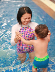 Fototapeta na wymiar Asian mother and baby boy swimming in pool training with happiness.