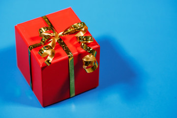 Gift, red box packed on a blue background, close-up. Holiday, New Year, Christmas, surprise. Flat lay, top view, space for text.