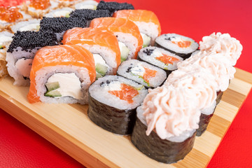 Assorted rolls and poppies. On the plank. On a red background.