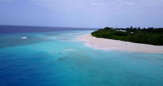 Static drone on top of crystal clear waters and a tropical island on the distance with sandy beaches in the Barbados, the Caribbean 4K