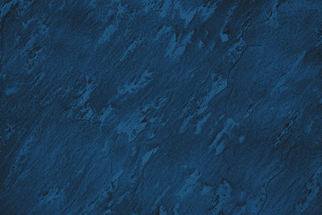 Dark blue colored low contrast stone textured background with roughness and irregularities to your design or product. Color trend concept.
