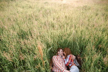 Naklejka na ściany i meble A guy and a girl lying in tall grass. Сountry.