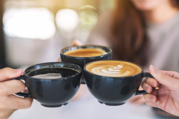 Closeup image of people enjoyed drinking and clinking coffee cups on the table in cafe