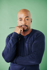 Pensive tired muscular man with circle beard taking off glasses and looking at camera