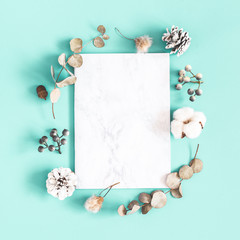 Winter composition. Dried leaves, cotton flowers, berries, pine cones on mint background. Christmas, winter concept. Flat lay, top view, copy space