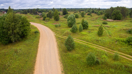 Fototapeta na wymiar Aerial view on a country road through the forest on a summer day