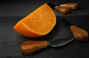 aged gouda cheese on black cut board with knives. It is crumbly, and delicious with hints of butterscotch, and lined with incredible sugar crystals. 
