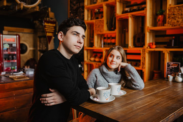 a young couple hugs in a cafe and drinks coffee