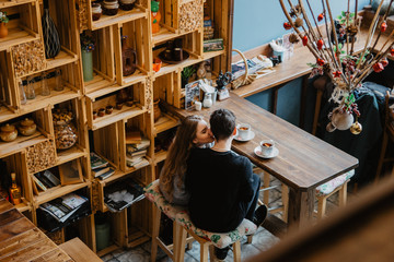 a young couple hugs in a cafe and drinks coffee