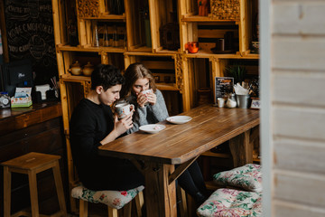 a young couple hugs in a cafe and drinks coffee