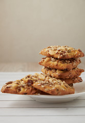 oat cookies chips and ingredients banana walnuts almonds raisin dried apricots on wooden table soft focus close up