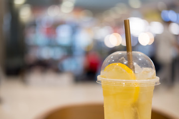 Iced tea mix with lemonade with lemons and gold straw in takeaway tall glass