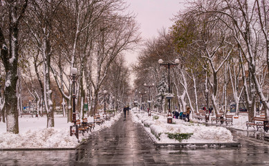 Snowfall in the winter city. Snowdrifts on the street and pedestrians