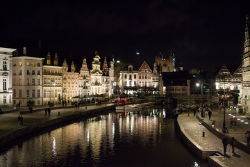 Fototapeta na wymiar Ghent, Belgium; 10/27/2019: Most famous canal in Ghent, Belgium, with reflections of the illuminated typical belgian houses on the water during the night, through Leie river (Lys river)