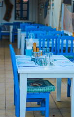 South Europe holiday concept: empty white tables and blue chairs, selective focus