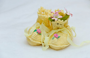 Yellow baby slippers and pink artifical flowers