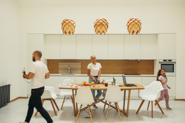 European family in white kitchen interior minimalism. Mother cooking dinner, child playing. Home, family concept