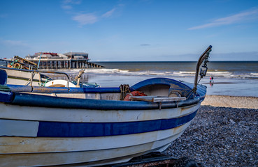 21 Traditional crab fishing boat in focus with an out of focus sea, pier and beach in the background
