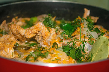 Meat with onions, carrots, dill and Bay leaf is stewed in a saucepan. Home cooking. Close up.