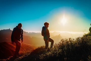 father and son hiking in sunset mountains, family travel