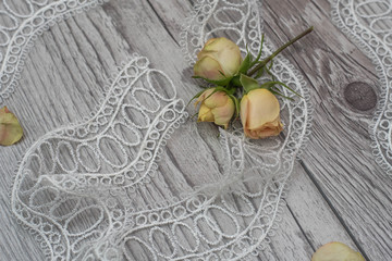 White wooden background with white spring flowers roses and lace ribbon. Happy womans day. The texture of lace on wooden background.