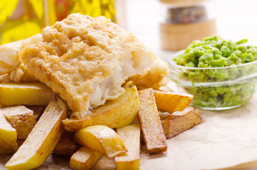 Traditional British street food fish and chips with mushy peas on parchment paper