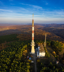 Obraz premium Tv tower on hill and autumn forest at sunset