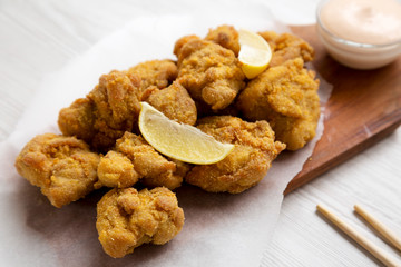 Homemade crispy japanese fried chicken Karaage on a rustic wooden board over white wooden surface, side view. Closeup.