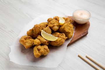 Homemade crispy japanese fried chicken Karaage on a rustic wooden board over white wooden background, side view. Close-up.