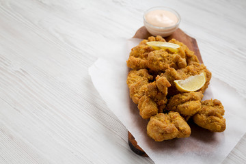 Homemade crispy japanese fried chicken Karaage on a rustic wooden board over white wooden background, side view. Copy space.